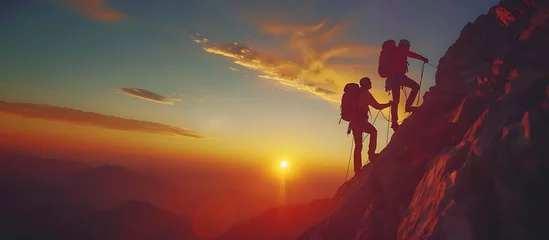 Fototapeten silhouette of a group of people helping each other to reach the top of a mountain in a sunset landscape © IA