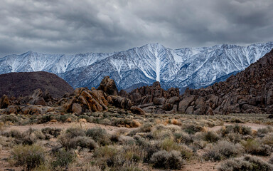 Cloudy sky on the mountains with snow and rocks on the foreground