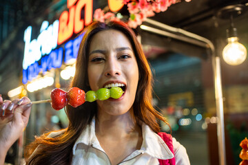 Portrait of Asian women eating street food while travel in city at night. 