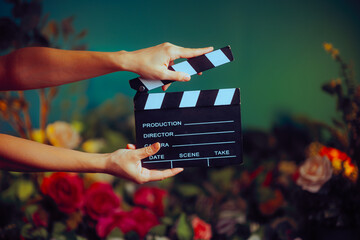 Director Holding a Film Slate on a Floral Background Set. Professional filmmaker producing a commercial using props 
