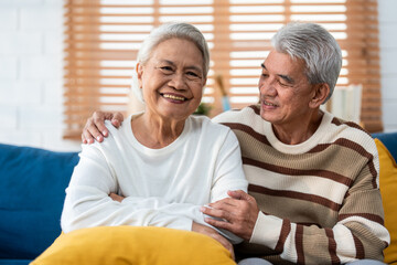 Portrait of Asian senior elderly couple sit on sofa in living room. 