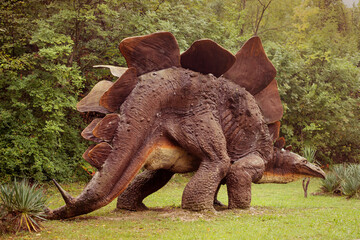 a large dinosaur sculpture in the garden. Realistic dinosaur sculpture.