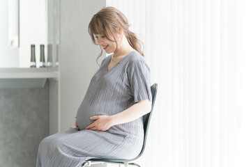 家のリビングで椅子に座る妊婦・マタニティフォト
