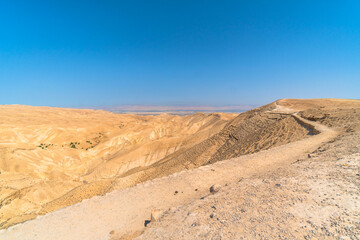 Hike to the dead sea horizon on clear blue sky day in the desert hot air
