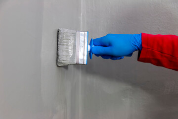 A builder worker applying waterproofing paint to the bathroom wall and floor. Applying waterproofing in the bathroom.