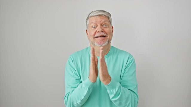 Joyful mature grey-haired man in casual clothes victoriously celebrating a win with an ecstatic smile and elated winner's expression, arms raised in triumph, isolated on a white background.