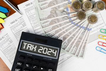 A calculator with the word tax 2024 on it is on top of a pile of money.