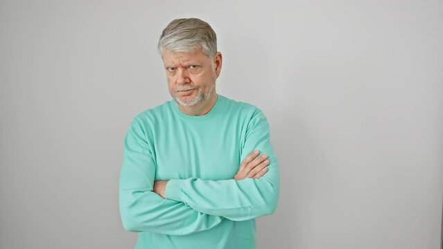 Skeptical grey-haired, middle-age man in casual attire, frowning with crossed arms. negative, disapproving look on his face. shot against an isolated white background.