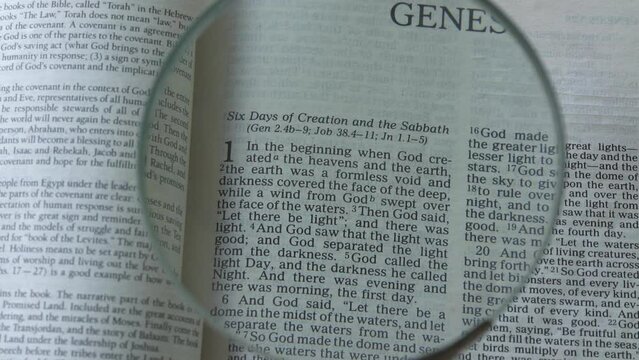 Book of Genesis of the old testament, Holy Bible. Using a magnifying glass to read text of chapter 1.