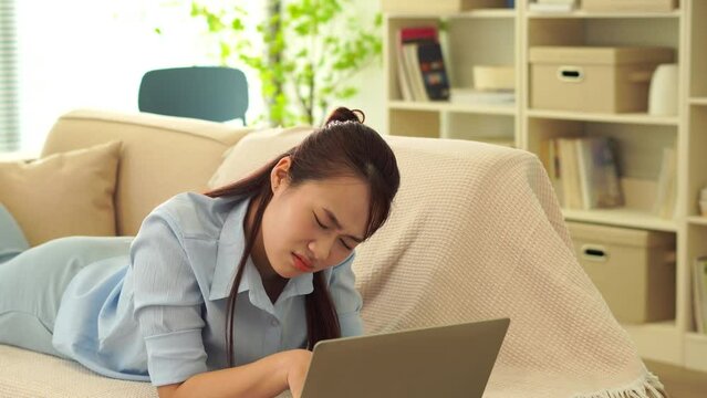 Asian woman using laptop with disappointed expression
