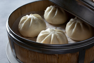 A closeup view of several steamed buns inside a bamboo steamer basket.