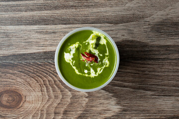 A top down view of a plastic container of saag paneer.