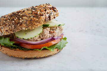 A view of a tuna salad bagel on teh left side of the frame.