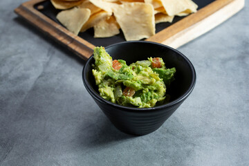A view of a black plastic condiment cup of guacamole.