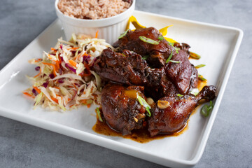 A view of a plate of brown stew chicken.