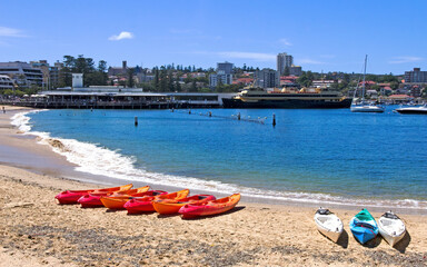 Kayaks on Manly cove beach with the ferry in the background