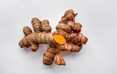 Fresh turmeric roots on a clean white background with space for text, ideal for healthy food and...