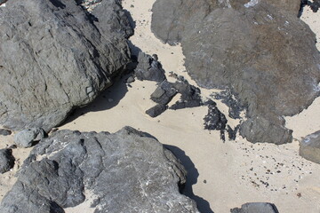 Sand accumulated between the boulders on a beach