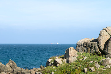 Seascape of the rock at the seaside and a ship on the horizon