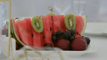 Plate with watermelon, peaches and grapes. Fruit slicing with watermelon, kiwi and grapes. Festive table at the banquet. Fruits on the holiday table.