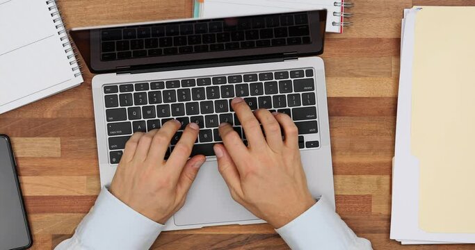 Finance analyst compiles report pressing keys on laptop