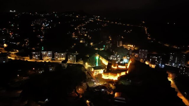 night time view of a city with a castle and a green light