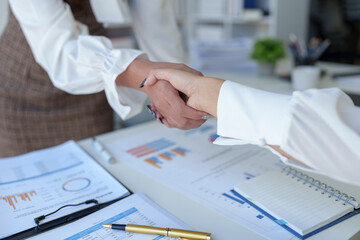 Two businesswoman shaking hands for success. Handshake. Collaboration, teamwork, friendship. Meeting of financial business partners, paperwork, calculations, investments, company partnerships.