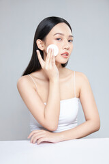 Attractive young Asian woman smile and uses cotton pad with toner for cleaning make up feeling so fresh and clean with healthy skin, isolated on white background. © Nguyen