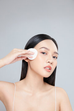 Attractive young Asian woman smile and uses cotton pad with toner for cleaning make up feeling so fresh and clean with healthy skin, isolated on white background.