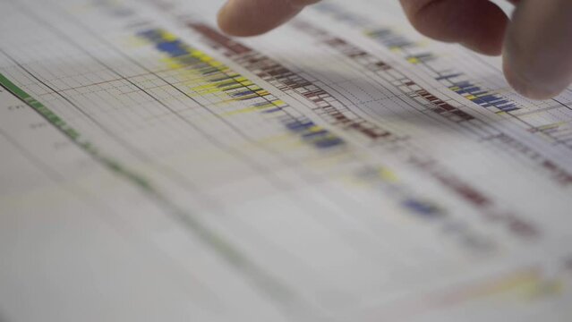 Close-up of a finger pointing at a detailed schedule or timeline chart