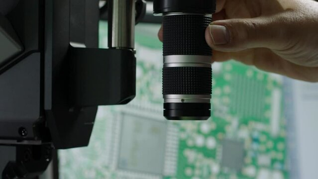 Close-up of a person's hand adjusting a camera lens, technology theme, indoors, selective focus