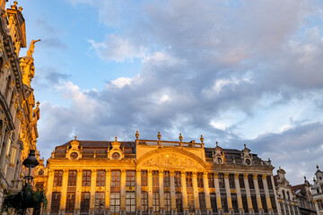 The historical guildhalls of Brussels' Grand Place bask in the warm light of the golden hour, with...