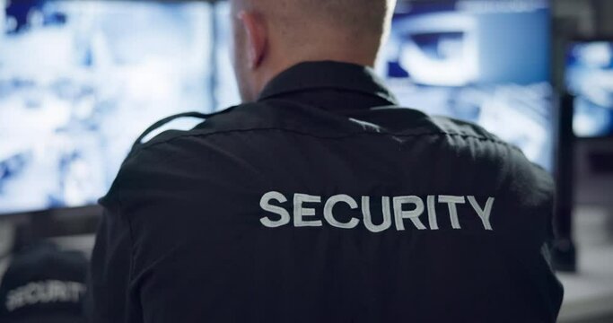 Security guard, computer screen and cctv surveillance on monitor for inspection service and building safety with rear view. Control room, protection officer and man with camera footage in data center
