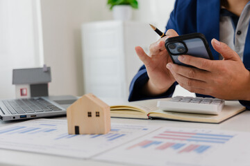 Man in a suit doing property tax calculations using a calculator of a house model