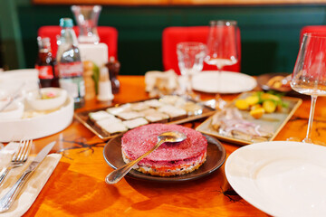 Served table with portioned Russian herring salad under a fur coat. 