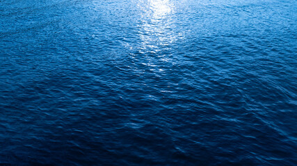 Deep sea waves, blue surface, of ocean navigation. There are ripples and bubbles. The sunlight shines brightly.	