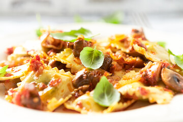 Ravioli with mushrooms and fresh basil. Bright wooden background. Close up.	