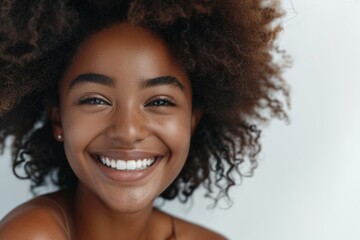 A woman with curly hair is smiling and has her teeth showing