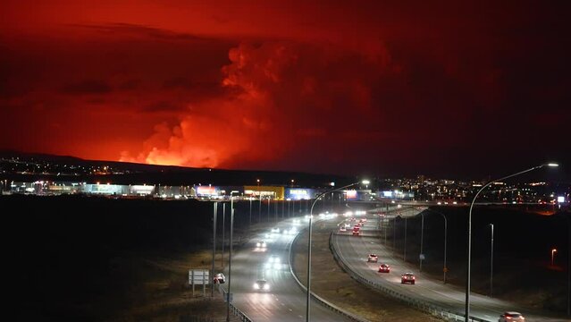 Red Horizon after Volcano Eruption in Iceland.at night. Traffic on highway in Iceland. Aerial wide shot. Dangerous scene with environmental pollution. Fumes rising into sky. Grindavik City, Iceland.
