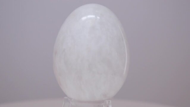 White Marble egg rotating slowly on a turntable in front of a white background.