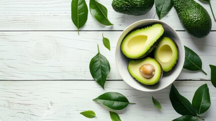 Half an avocado with green leaves on a whitewashed wooden background, perfect for healthy food lovers and vegan enthusiasts looking for fresh and delicious meal inspiration - obrazy, fototapety, plakaty