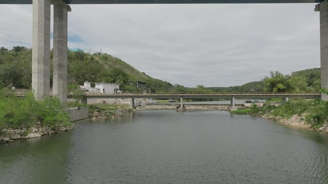 Drone flying under bridge crossing Rio Chavon river, Dominican Republic. Aerial forward at low altitude