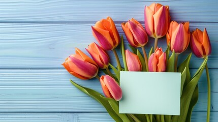 Vibrant orange tulips with a blank white card on a distressed blue wooden background