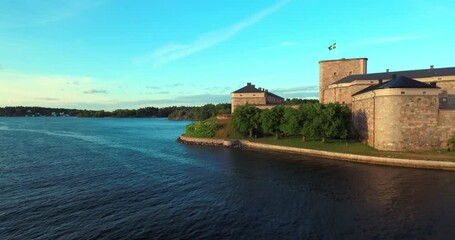 Aerial: Dusk Light Caresses The Walls Of Stockholm'S Fortress With The Swedish Flag Flying High, Overseeing The Tranquil Waters Of The Archipelago