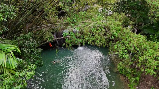 Drone footage of a waterfall with one swimmer on Siquijor island in the Philippines.