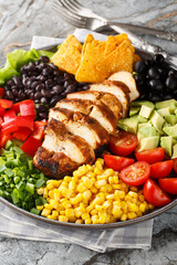 Obraz na płótnie Canvas Southwest Salad or Santa Fe Salad is the perfect blend of fresh ingredients like lettuce, tomatoes, corn, black beans and juicy chicken breast closeup on the plate on the table. Vertical