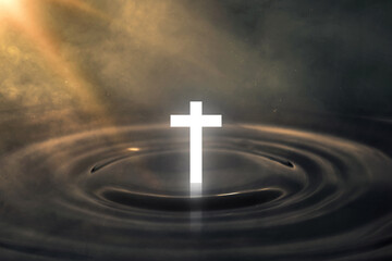 Religious cross of Jesus Christ on a water surface with sunbeam liaght in the dark background