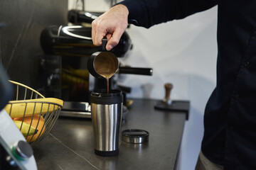 Fototapeta na wymiar Man pouring homemade coffee into the travel mug