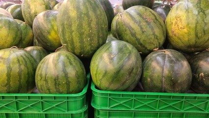 Pile of fresh watermelons (Citrullus lanatus) on the market. Watermelon is a sweet, commonly...