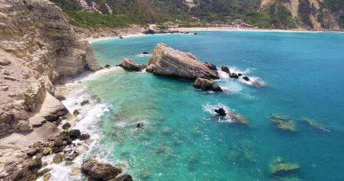Retreating drone shot of the rocky beachfront of Petanoi, an isolated resort located in Kefalonia in the West Coast of Greece.